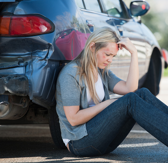 a woman sitting on the ground next to a car